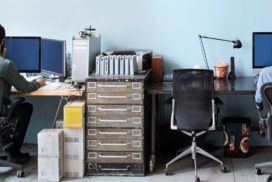 On either end of the photo, two developers work. A vintage filing cabinet sits between their desks.
