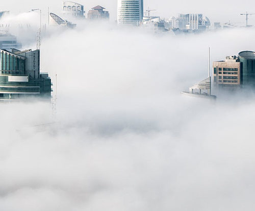 An aerial view of a city enveloped in clouds.