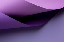 Curved sheets of purple paper overlap each other on a flat, light purple surface.
