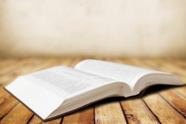 An open dictionary lies on a wooden table