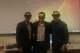 Three men wearing 3d glasses in front of a projector.