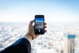 Business man holding mobile phone over a city skyline