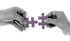 Black and white photo of hands fitting puzzle pieces together