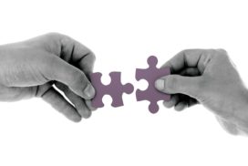 Black and white photo of hands fitting puzzle pieces together