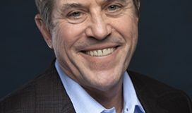 A man in a suit smiling for the camera.