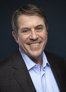 A man in a suit smiling for the camera.