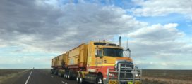 A semi trailer truck driving down a rural highway