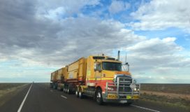 A semi trailer truck driving down a rural highway