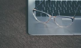 Glasses rest upon an open laptop