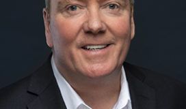 A man in a suit smiling for the camera.