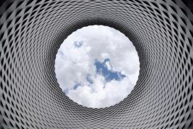 A picturesque image of a circular structure amidst a captivating sky adorned with fluffy clouds.