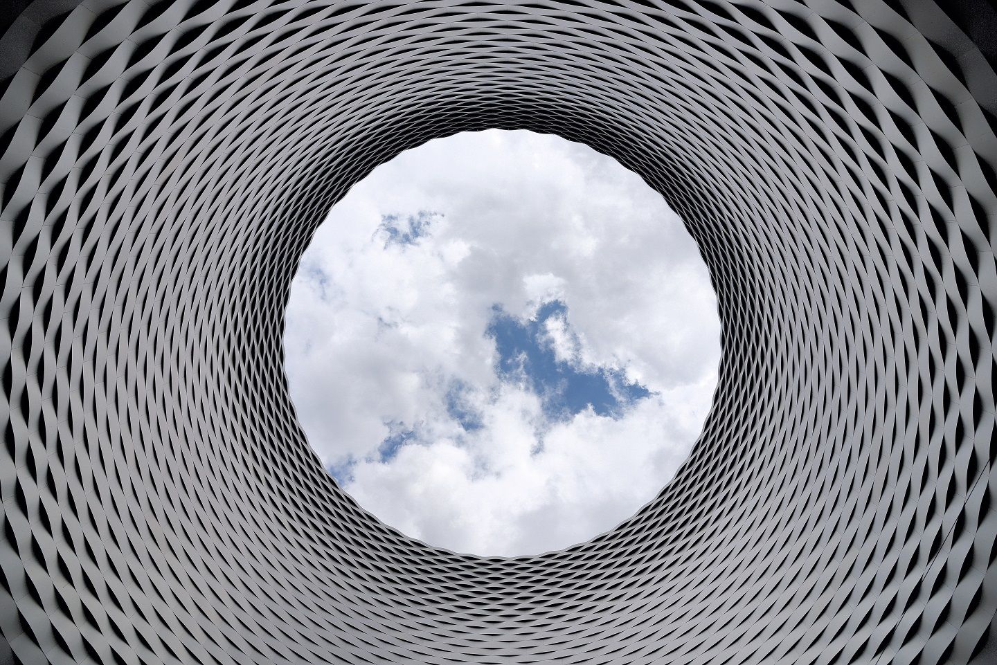 A picturesque image of a circular structure amidst a captivating sky adorned with fluffy clouds.