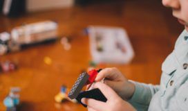 A young boy engrossed in his play, creating intricate structures with legos on a smooth wooden floor.