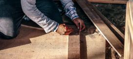 A man is working on a wooden floor.