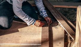 A man is working on a wooden floor.