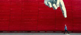 A red building with a large hand painted on it is featured in this mobile app.