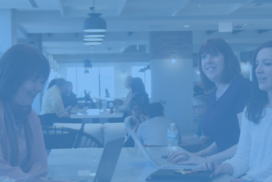 Five women sitting around a table in a cafe working.