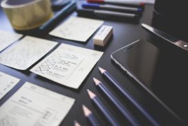 Neatly arrayed office supplies and a smartphone lie on a black desk.