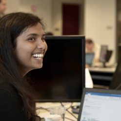 A laughing woman working in an open concept office.