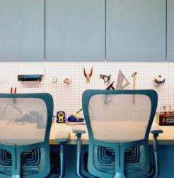 Office chairs sit in front of a work bench in a maker space. Tools hang on peg board.