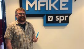 A man standing in front of a make spr sign.