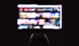 A remote control in front of a tv screen.