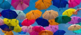 A bunch of colorful umbrellas flying in the air.