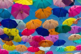 A bunch of colorful umbrellas flying in the air.