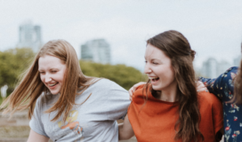 A group of women are laughing together in front of a city.