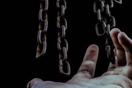 A person's hand reaching out to a chain.