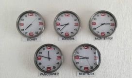 Four clocks are lined up on a white wall.