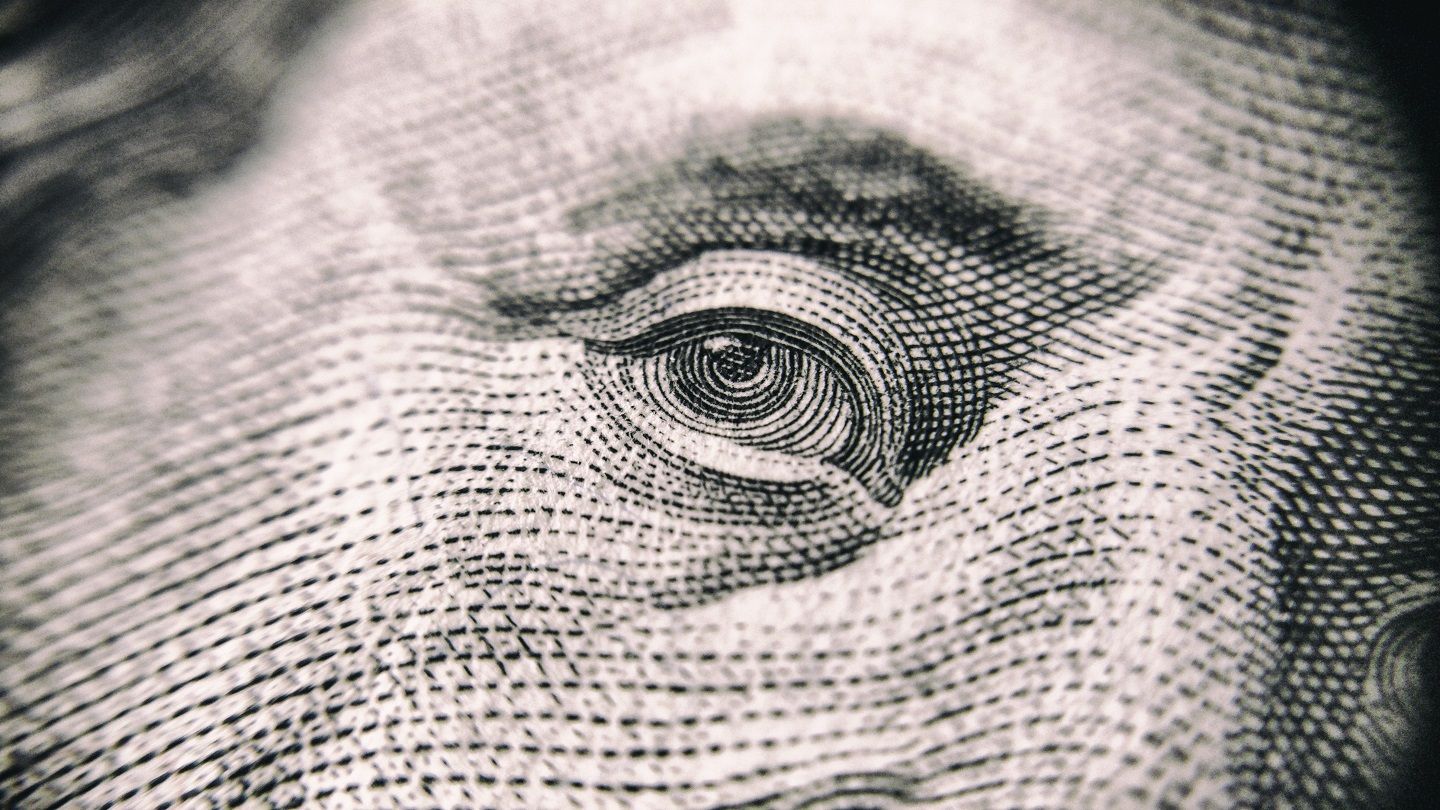 A close up of a man's eye on a dollar bill.