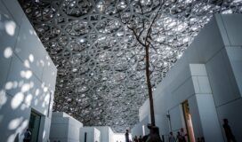 The ceiling of a museum with people walking through it.