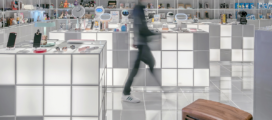 A person walking through a store with shelves full of cosmetics.