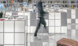 A person walking through a store with shelves full of cosmetics.