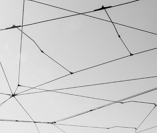A black and white photo showcasing a network of wires suspended in the sky.