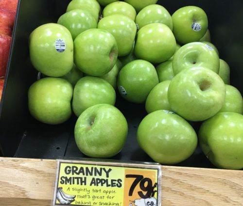 A display of green apples in a grocery store.