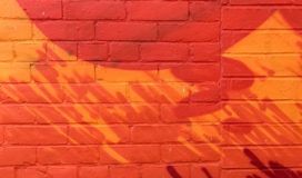A red and orange mural on a brick wall.