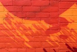 A red and orange mural on a brick wall.