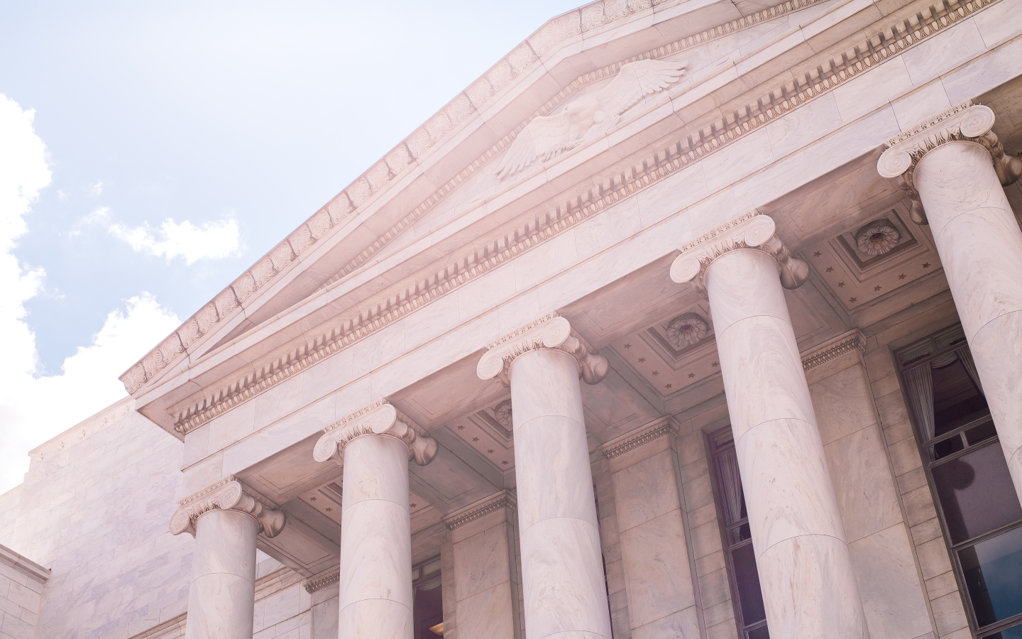 A white building with columns and a blue sky.