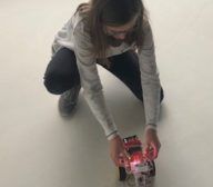 A girl kneeling on the floor with a toy robot.