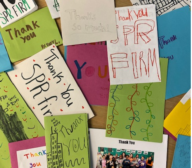 Many thank you cards are laying on a table.