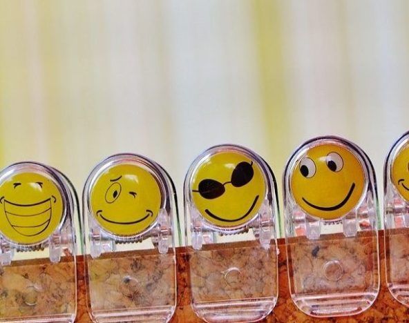 A row of smiley faces on a cork board.