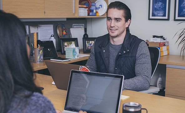 A man sitting at a desk with a laptop in front of him.