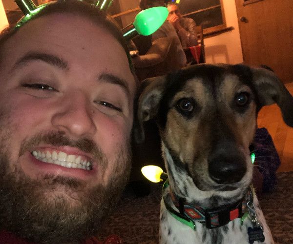 Close up of a smiling adult male and a small dog.