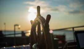 The helm on a boat at sunset.