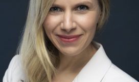 A blond woman in a white jacket