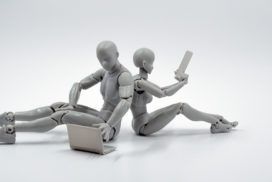 Two mannequins utilizing AutoML, sitting on the ground and holding a laptop.
