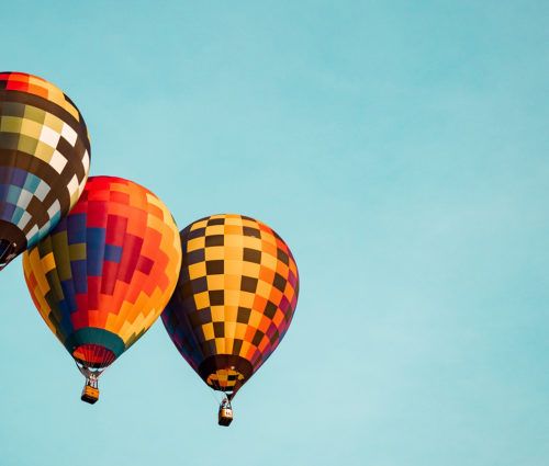 Three DevTestOps colorful hot air balloons flying in the sky.