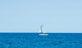 A sailboat sailing gracefully in the vast ocean.